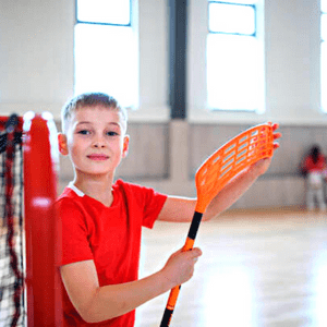With the floorball stick a boy is playing the game