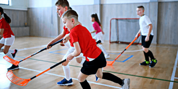 A group of young boys playing indoor floorball game.