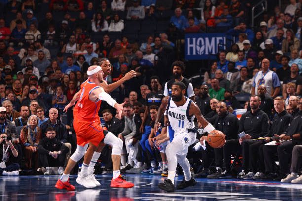 Thunder vs. Mavericks: Kyrie Irving, wearing #11 for the Dallas Mavericks, surveys the court as he looks to make a pass.